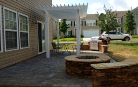 Paver Patio with ledge stone fire pit and sitting wall and a wood pergola with an outdoor kitchen in Ft. Mill, SC