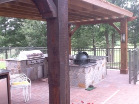 Archadeck of Charlotte designed and built this cedar pergola in south Charlotte with a fieldstone outdoor kitchen and Green Egg